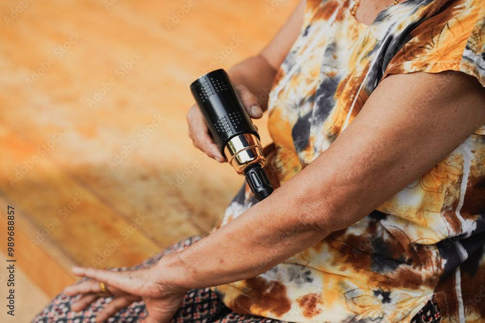 Fototapeta premium A close-up view of an individual using a tattoo machine on their arm, showcasing artistry and body decoration in a vibrant and colorful environment.