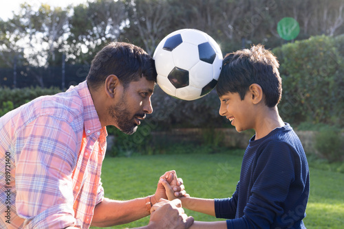 Indian father and son playing with soccer ball, enjoying outdoor bonding time