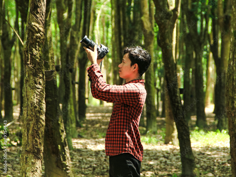 Southeast Asian youth photographing wildlife in a forest Southeast Asian youth photographing wildlife in a forest