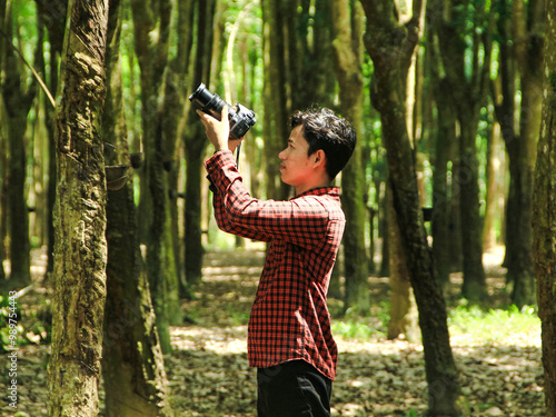 Southeast Asian youth photographing wildlife in a forest