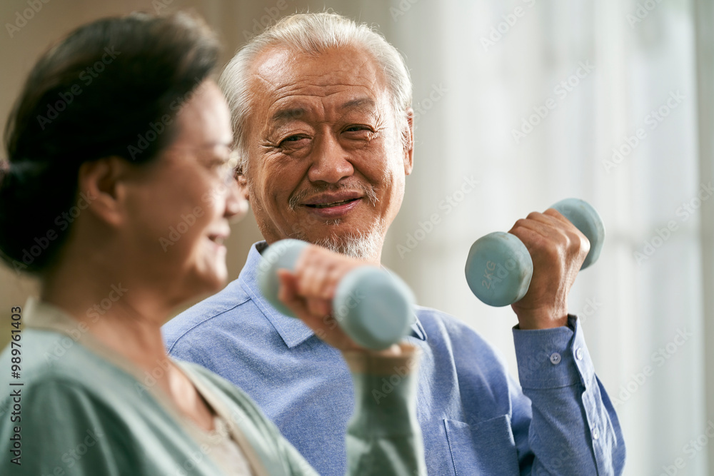 happy senior asian couple exercising at home using dumbbells happy senior asian couple exercising at home using dumbbells