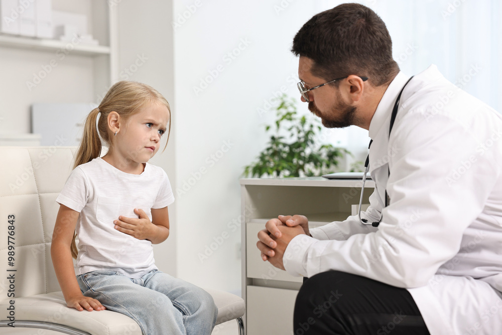 Fototapeta premium Doctor consulting little girl with stomach pain in hospital