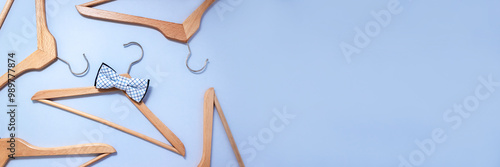 Wooden hanger with checkered bow tie surrounded by other clothes hangers. Men sale banner. Selective focus, copy space