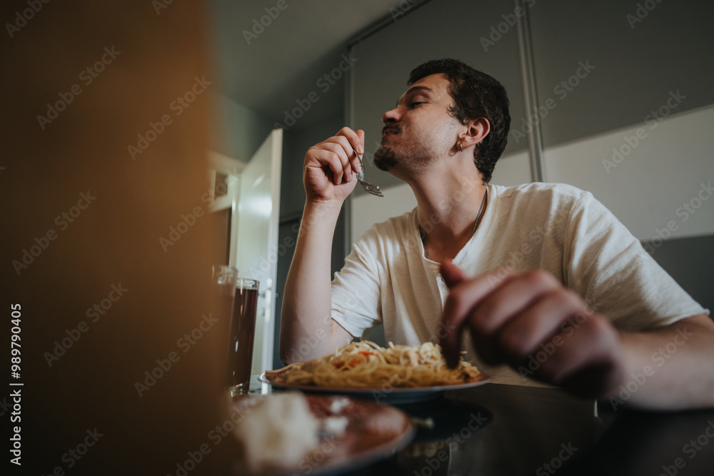 A man savors a flavorful plate of pasta while dining at home, capturing the pleasure of a homemade meal. A man savors a flavorful plate of pasta while dining at home, capturing the pleasure of a homemade meal.