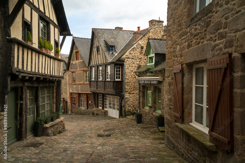 View of the medieval street of the city with half-timbered houses descending to the embankment of the Rance River on a sunny summer day, Dinan, Cotes-d'Armor, Brittany, France View of the medieval street of the city with half-timbered houses descending to the embankment of the Rance River on a sunny summer day, Dinan, Cotes-d'Armor, Brittany, France