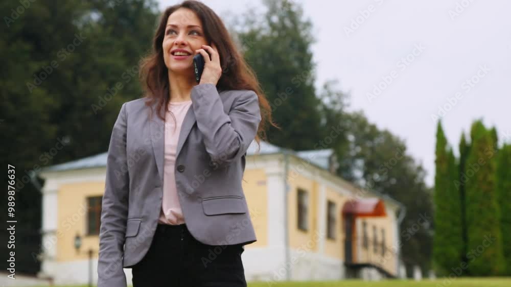 Beautiful happy toothy smiling business woman in grey suit talking on the mobile phone outdoor nature summer green background
Beautiful happy toothy smiling business woman in grey suit talking on the mobile phone outdoor nature summer green background