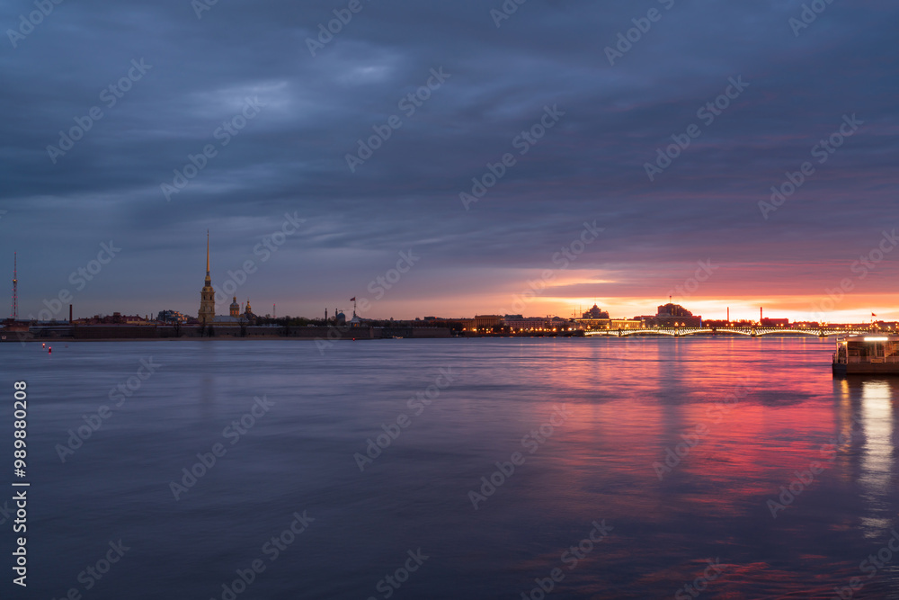 View of the Peter and Paul Fortress and the Neva River against a pink dawn sky with clouds on a sunny spring morning, St. Petersburg, Russia View of the Peter and Paul Fortress and the Neva River against a pink dawn sky with clouds on a sunny spring morning, St. Petersburg, Russia