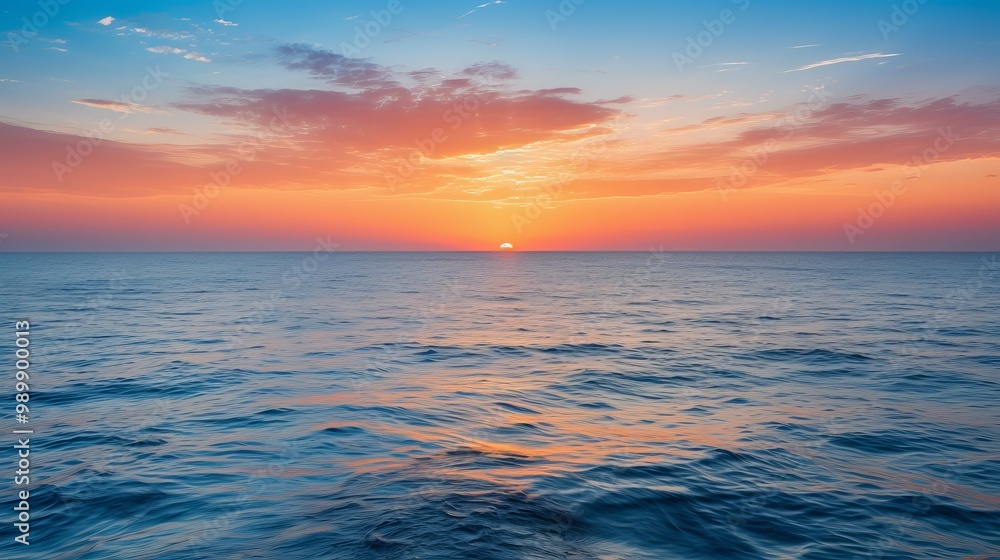 Naklejka premium Serene sunset over calm ocean waters with vibrant colors near the horizon