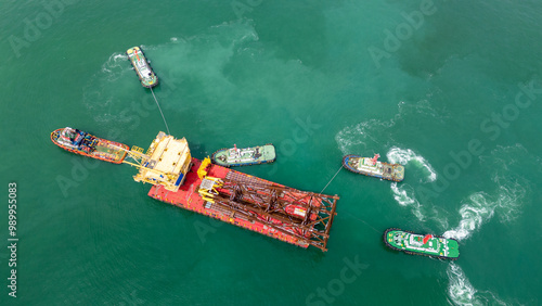 Big Construction on ship. Tender Drilling Oil Rig on Barge Ship transportation Rid to Oil Rig in The Middle of The Ocean. Five Tug boat pulling Construction photo