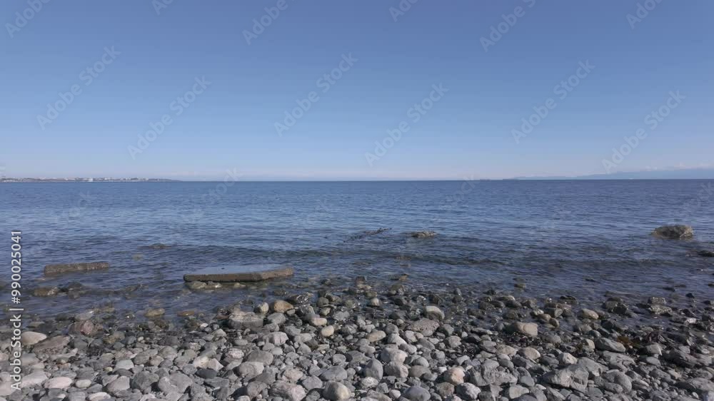 Calm blue waters of a rocky shoreline under a clear sky at Royal Roads Bay Calm blue waters of a rocky shoreline under a clear sky at Royal Roads Bay