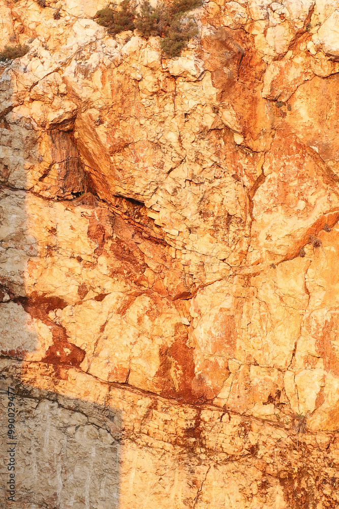 Naklejka premium Sunlit rocky cliff with textured stone surface