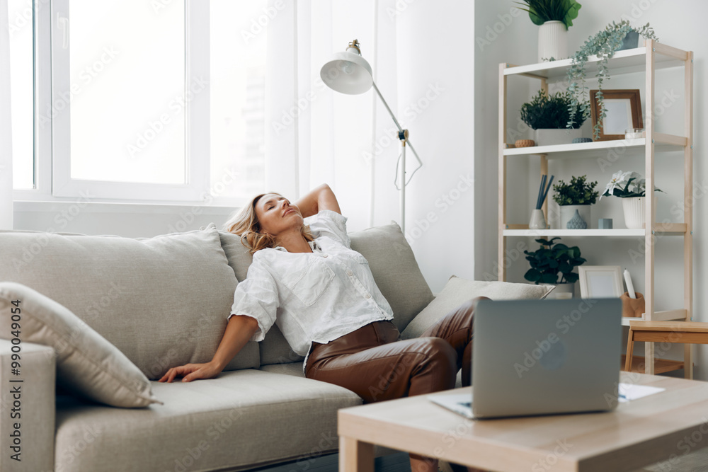 Woman relaxing on couch with laptop and coffee table, enjoying a casual day indoors Woman relaxing on couch with laptop and coffee table, enjoying a casual day indoors