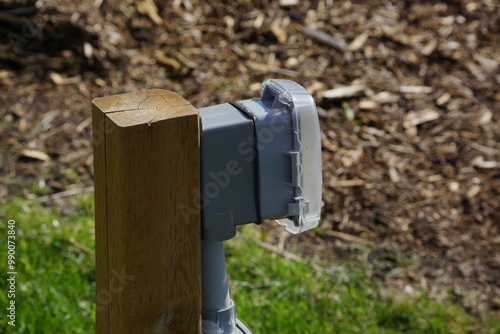 Outdoor outlet with protective cover on grass and wood bark chips