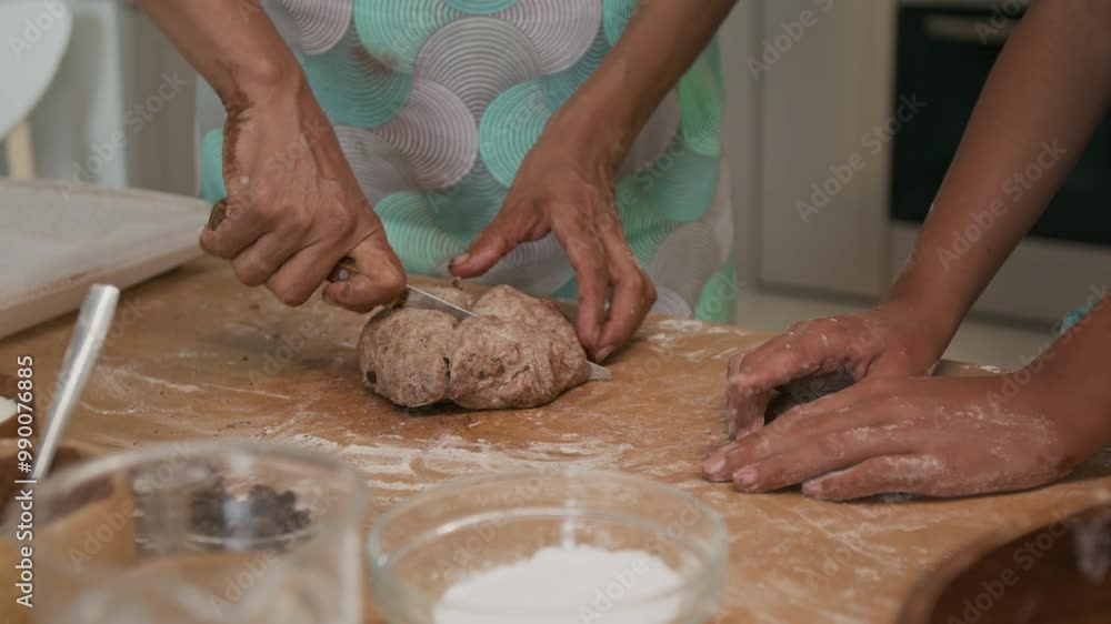 Midsection close-up shot of hands of unrecognizable woman cutting chocolate cookie dough into four pieces using knife while preparing homemade pastry with child at home Midsection close-up shot of hands of unrecognizable woman cutting chocolate cookie dough into four pieces using knife while preparing homemade pastry with child at home