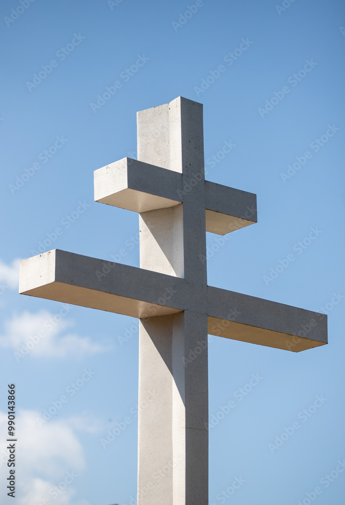 A white cross with three pillars is standing in a blue sky A white cross with three pillars is standing in a blue sky