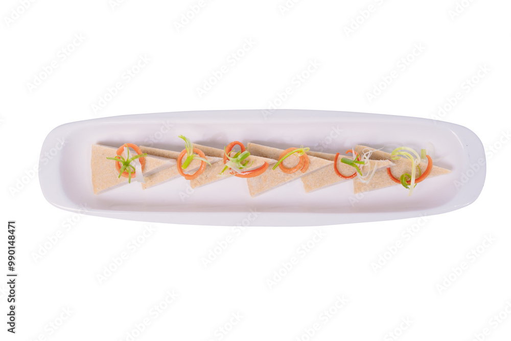 A rectangular plate holds a row of triangular slices of steamed pork roll, garnished with shredded carrots and green onions. A rectangular plate holds a row of triangular slices of steamed pork roll, garnished with shredded carrots and green onions.