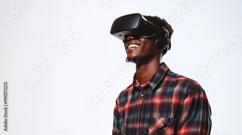 A young man enjoys a virtual reality experience, wearing a VR headset and smiling with excitement. Ideal for tech and gaming themes.