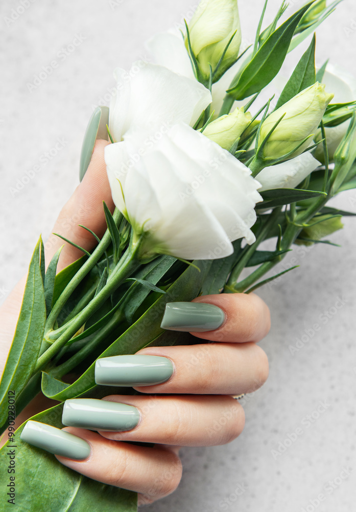A hand holding a delicate bouquet of white flowers against a soft textured background during daylight A hand holding a delicate bouquet of white flowers against a soft textured background during daylight