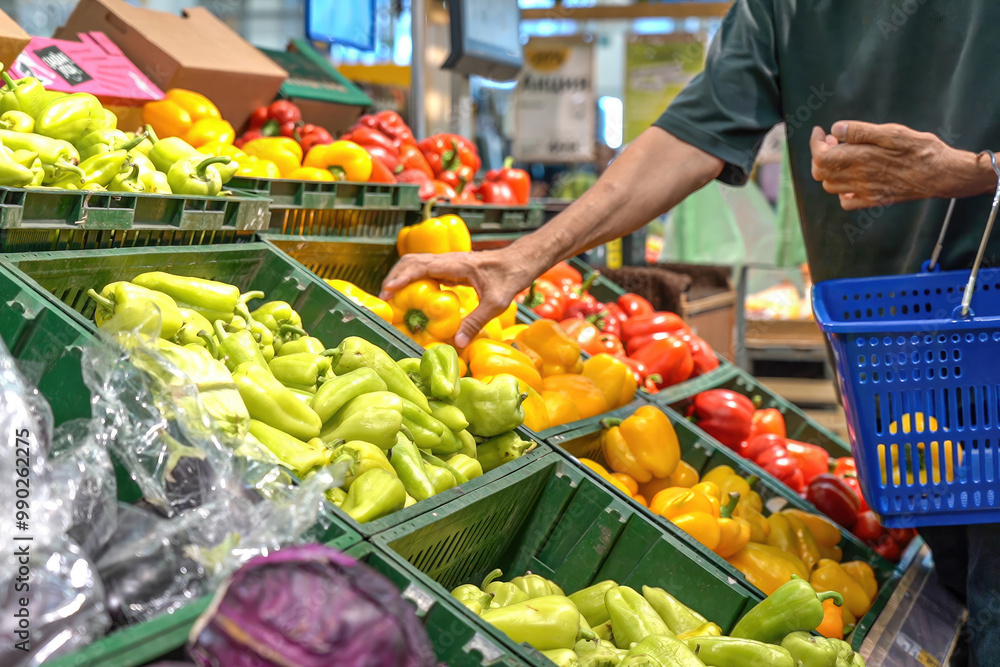 Mature man chooses yellow bell peppers in supermarket Mature man chooses yellow bell peppers in supermarket