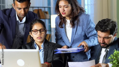 A young Indian team of professionals or businessmen working together looking over project documents and showing slight disappointment with the results while discussing how to make things better