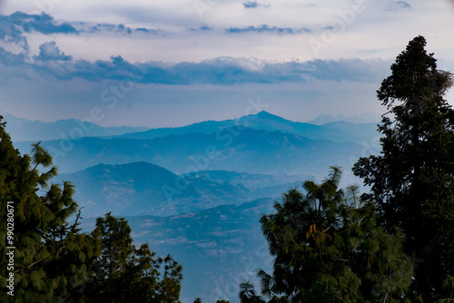 Stunning panorama of mountainous landscape with lush greenery and dramatic clouds under clear sky in the afternoon light