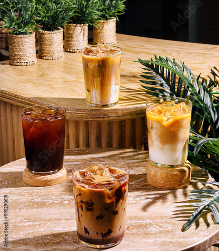 Four iced coffee drinks sitting on a cafe table in the sun