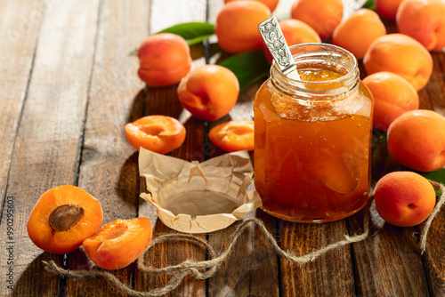 Fotografie Apricot jam and fresh fruit on an old wooden table.