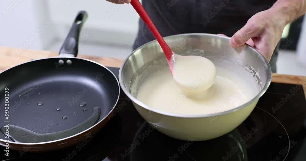 Male hands scoop up batter using ladle pouring onto hot frying pan. Man chef engages in cooking delicious pancakes for breakfast in kitchen Male hands scoop up batter using ladle pouring onto hot frying pan. Man chef engages in cooking delicious pancakes for breakfast in kitchen
