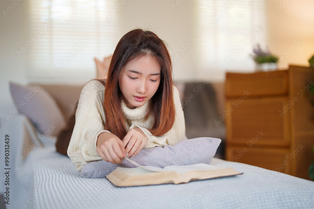 Young asian women in sweater lying on comfortable couch to enjoying and happiness with reading literature book while relaxation and doing activity to spending time with slow life lifestyle at home Young asian women in sweater lying on comfortable couch to enjoying and happiness with reading literature book while relaxation and doing activity to spending time with slow life lifestyle at home