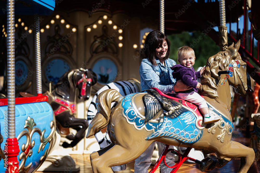 Mother and child enjoying a carousel ride on a sunny day Mother and child enjoying a carousel ride on a sunny day