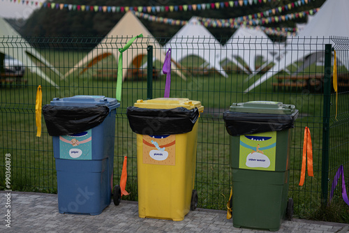 Colorful recycling bins at outdoor event with tents