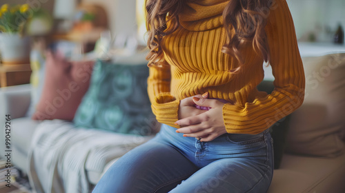 Woman at home suffering from menstrual pain, having cramps. Close up of woman holding abdomen, endometriosis, and conditions causing pain in tummy