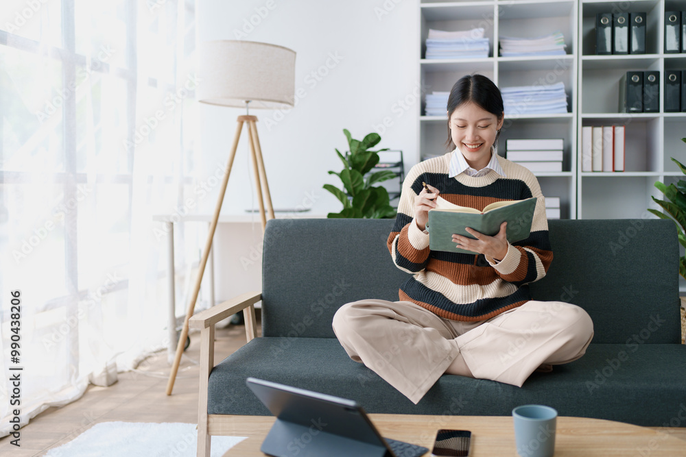 A woman sits on a sofa, using her notebook and tablet computer simultaneously to study online, efficiently managing her learning through digital platforms from the comfort of her home A woman sits on a sofa, using her notebook and tablet computer simultaneously to study online, efficiently managing her learning through digital platforms from the comfort of her home