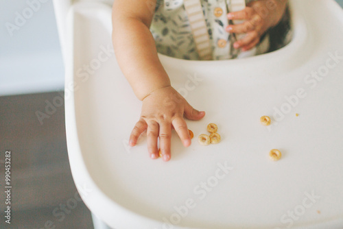 A baby's hand picking up cheerios in their high chair. photo