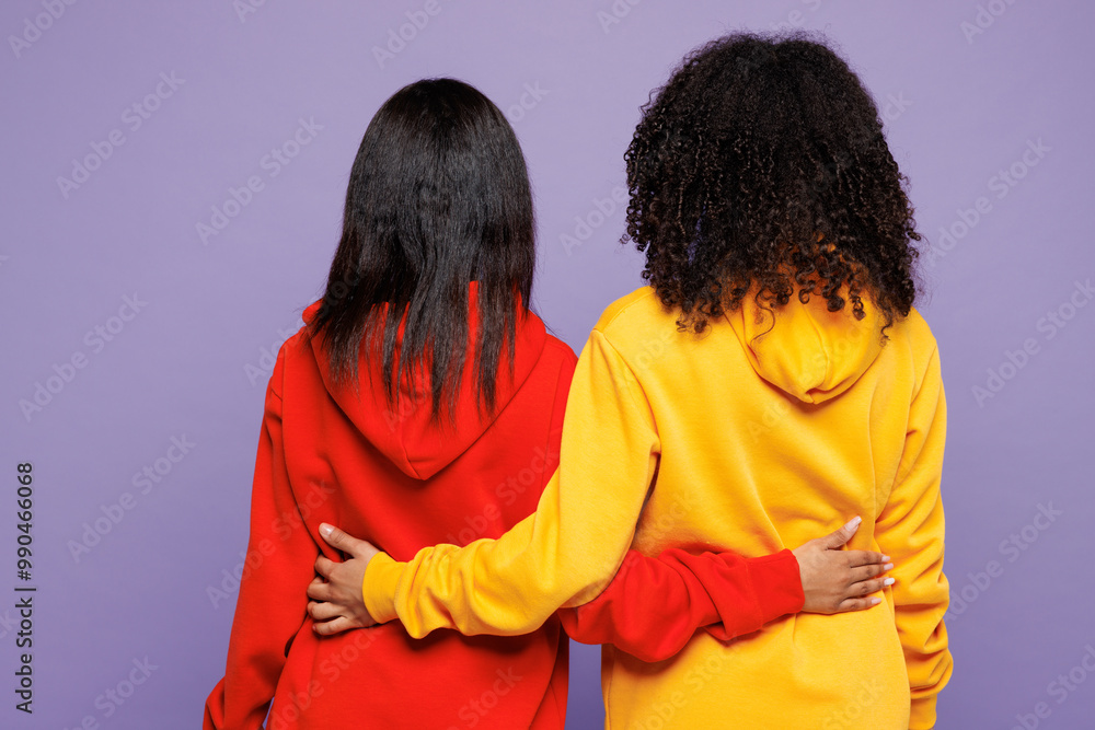 Obraz premium Rear view of two young little kid teen girls women they wear red yellow hoodie casual clothes hug embrace put hands on back of each other isolated on plain pastel purple background. Lifestyle concept.