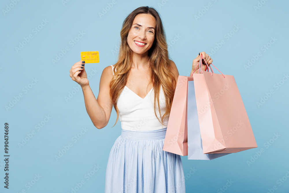 Young fun woman wear casual clothes hold in hand paper package bags after shopping mock up of credit bank card isolated on plain light pastel blue cyan background. Black Friday sale buy day concept. Young fun woman wear casual clothes hold in hand paper package bags after shopping mock up of credit bank card isolated on plain light pastel blue cyan background. Black Friday sale buy day concept.