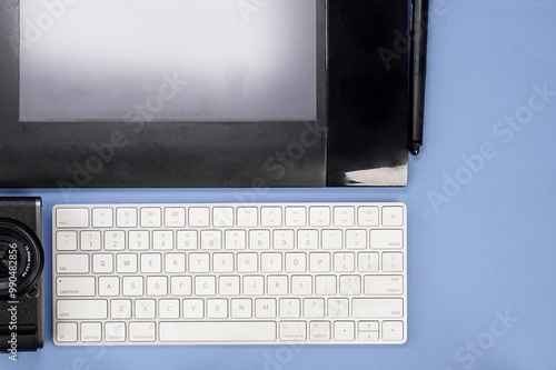 graphic tablet with pen for illustrator, keyboard and camera on blue background