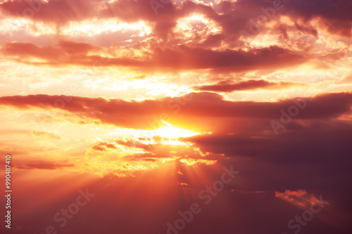 A dramatic sunset with glowing orange and pink light rays breaking through clouds, creating a stunning sky scene photo