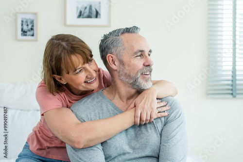 Caucasian senior older couple sitting on bed then look outside window. 