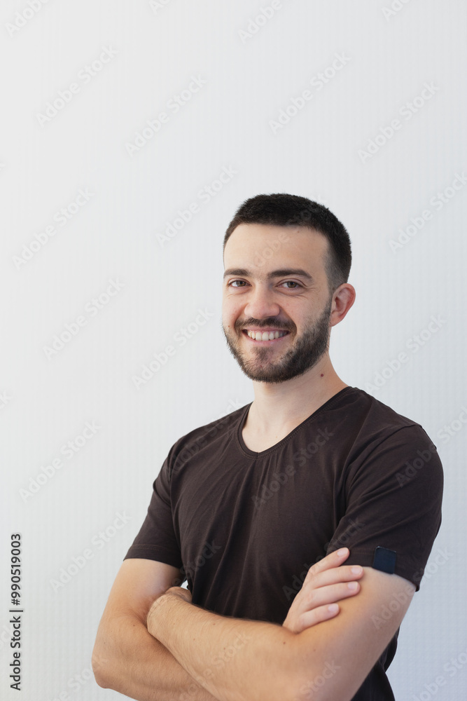 Portrait of an yoang smiling man in a casual t-shirt on the light gray background with a place for lettering Portrait of an yoang smiling man in a casual t-shirt on the light gray background with a place for lettering