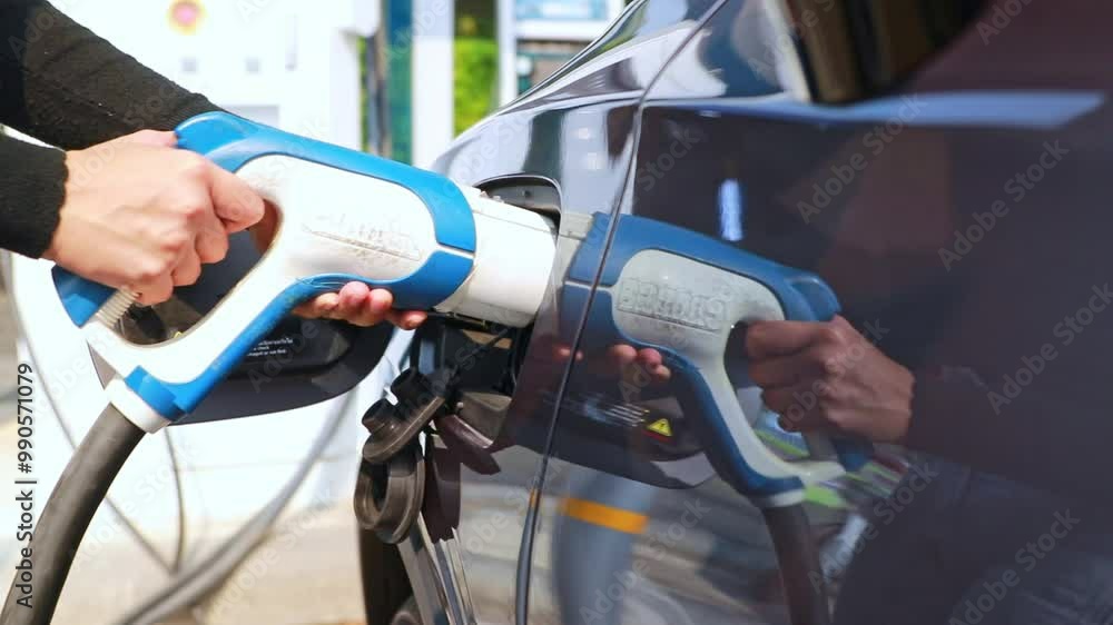 Young woman's hand driving an EV car is safely closing the charging plug and cover of her EV car inside gas station after charging is complete. Young woman's hand driving an EV car is safely closing the charging plug and cover of her EV car inside gas station after charging is complete.