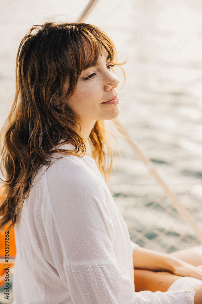 A woman in a white shirt relaxes on a sailboat, enjoying the tranquility of the sea. Her peaceful expression reflects a sense of calmness and contentment. A woman in a white shirt relaxes on a sailboat, enjoying the tranquility of the sea. Her peaceful expression reflects a sense of calmness and contentment.