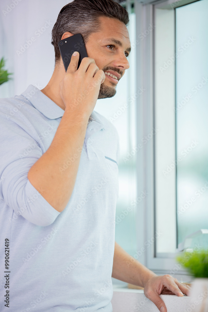 man stood by window using his smartphone man stood by window using his smartphone