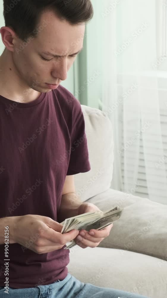 Serious Caucasian young adult man counting salary holding stack of cash at home. Money income and investment concept. Vertical video. Serious Caucasian young adult man counting salary holding stack of cash at home. Money income and investment concept. Vertical video.