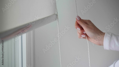 Woman pulling cord to open blinds, closeup