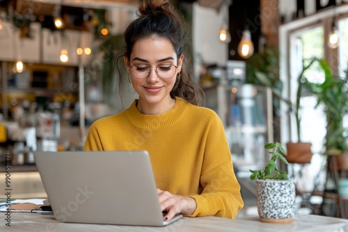 Young woman working on a laptop in a cozy cafe, enjoying a productive remote work environment.