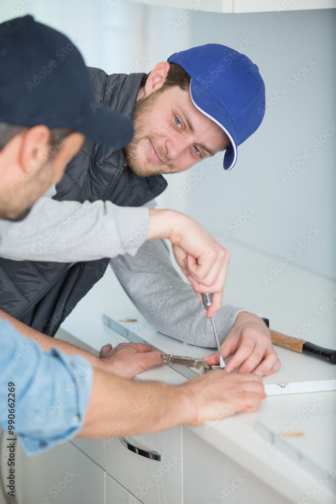 man assembling hinge on kitchen cupboard using screwdriver man assembling hinge on kitchen cupboard using screwdriver