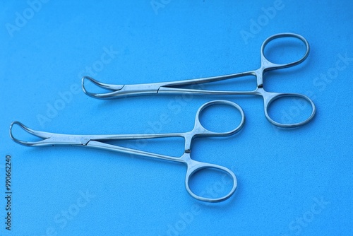 two medical surgical sterile iron silver industrial shiny closed professional sharp pincers lie on blue table in operating room photo