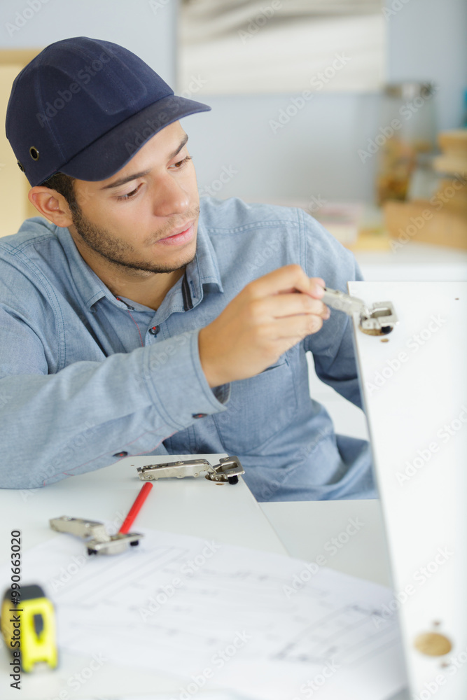 Fototapeta premium young man fitting wardrobe in kitchen cabinet