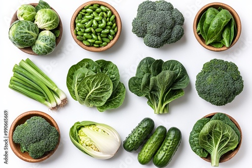 Fresh green vegetables like spinach, broccoli, and cucumbers arranged neatly on a white background. photo